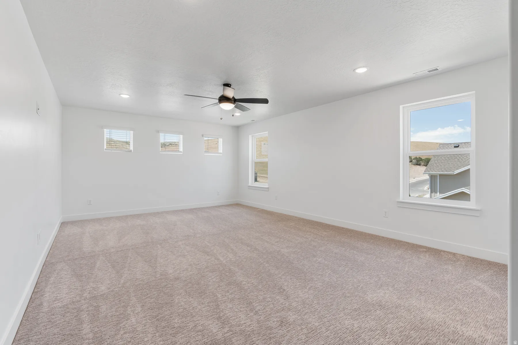 Unfurnished room with light colored carpet, a ceiling fan, recessed lighting, and a textured ceiling