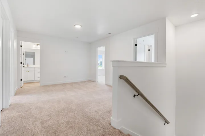 Hallway with an upstairs landing, light colored carpet, and recessed lighting