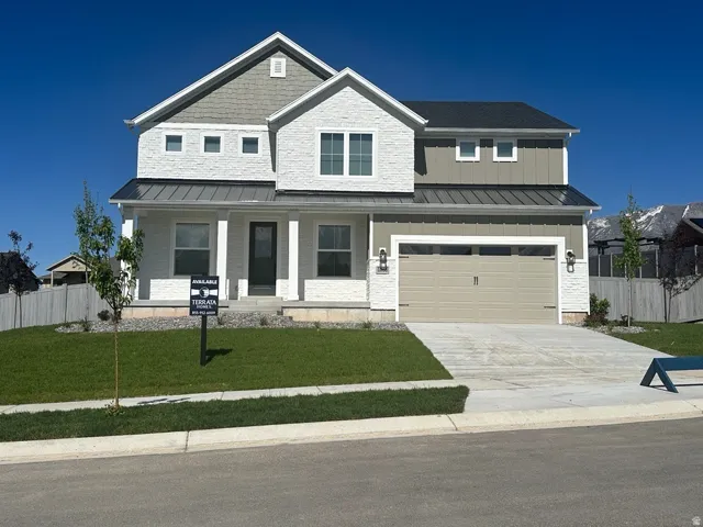 View of front of property with a standing seam roof, a metal roof, covered porch, concrete driveway, and board and batten siding