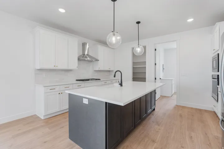 Kitchen with backsplash, white cabinets, an island with sink, light wood finished floors, and recessed lighting
