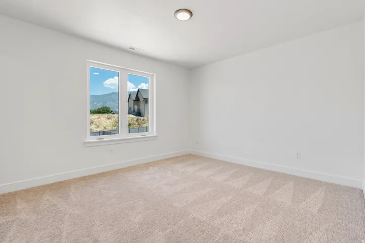 Empty room with light colored carpet and a mountain view