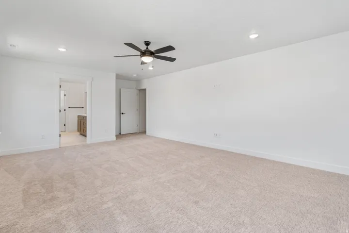 Unfurnished bedroom with light carpet, ceiling fan, recessed lighting, and ensuite bathroom
