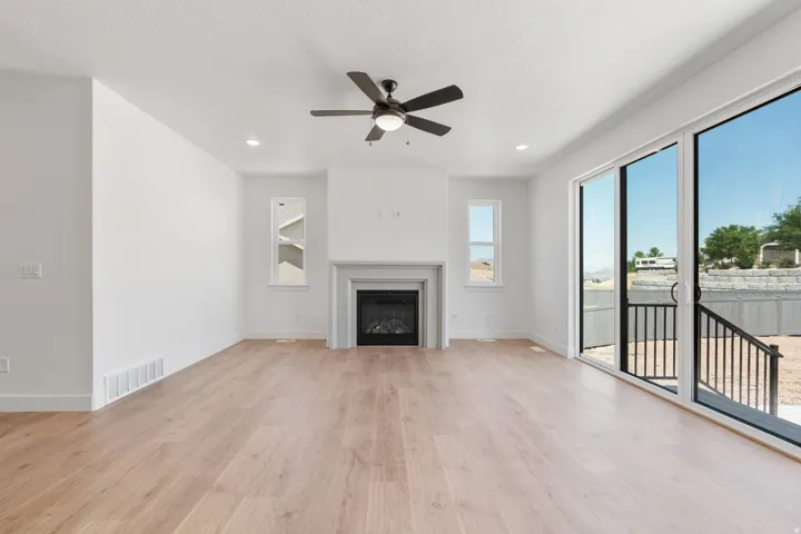 Unfurnished living room with light wood-style flooring, a ceiling fan, a glass covered fireplace, and recessed lighting
