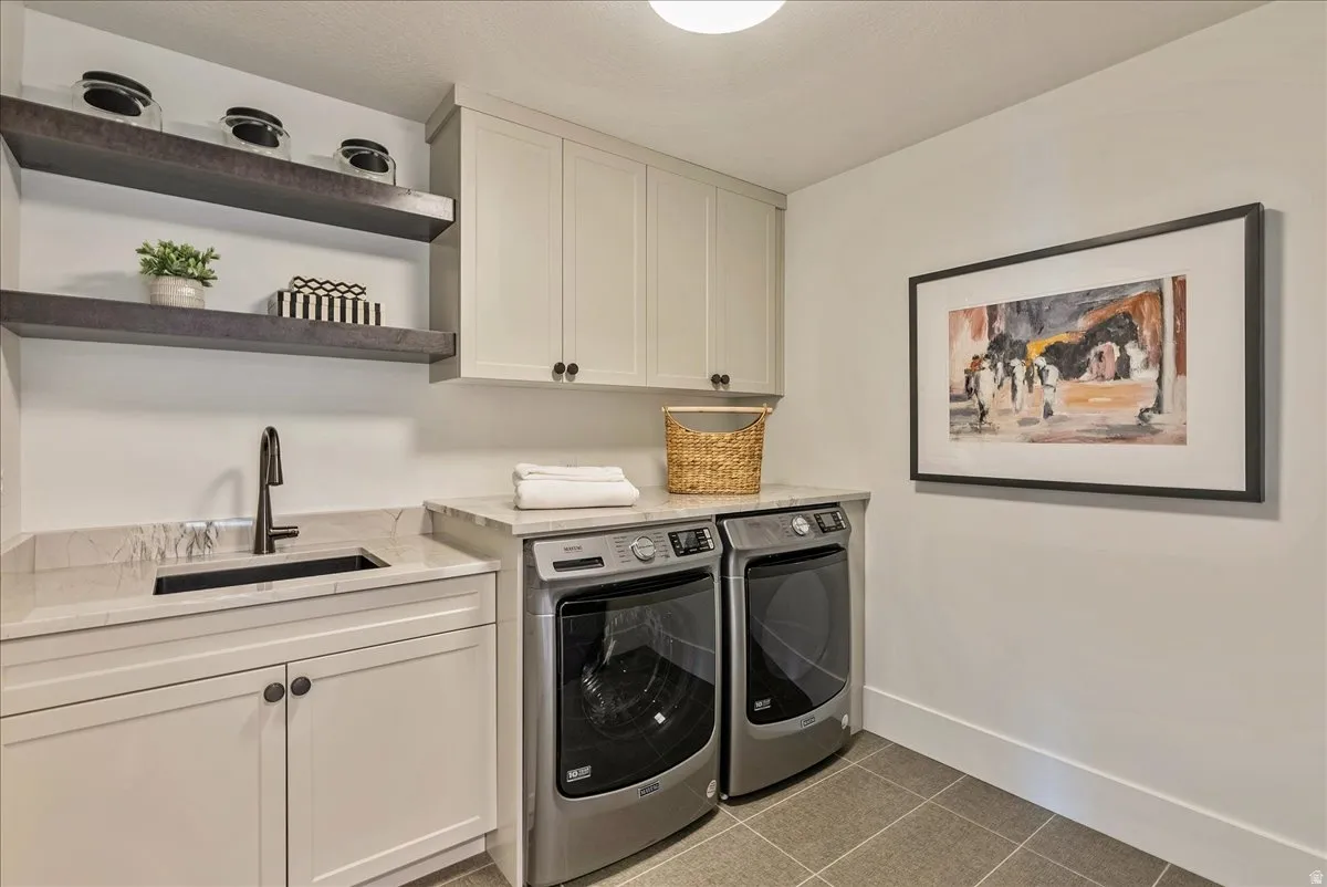 Laundry area with light tile patterned floors, cabinet space, and washing machine and dryer
