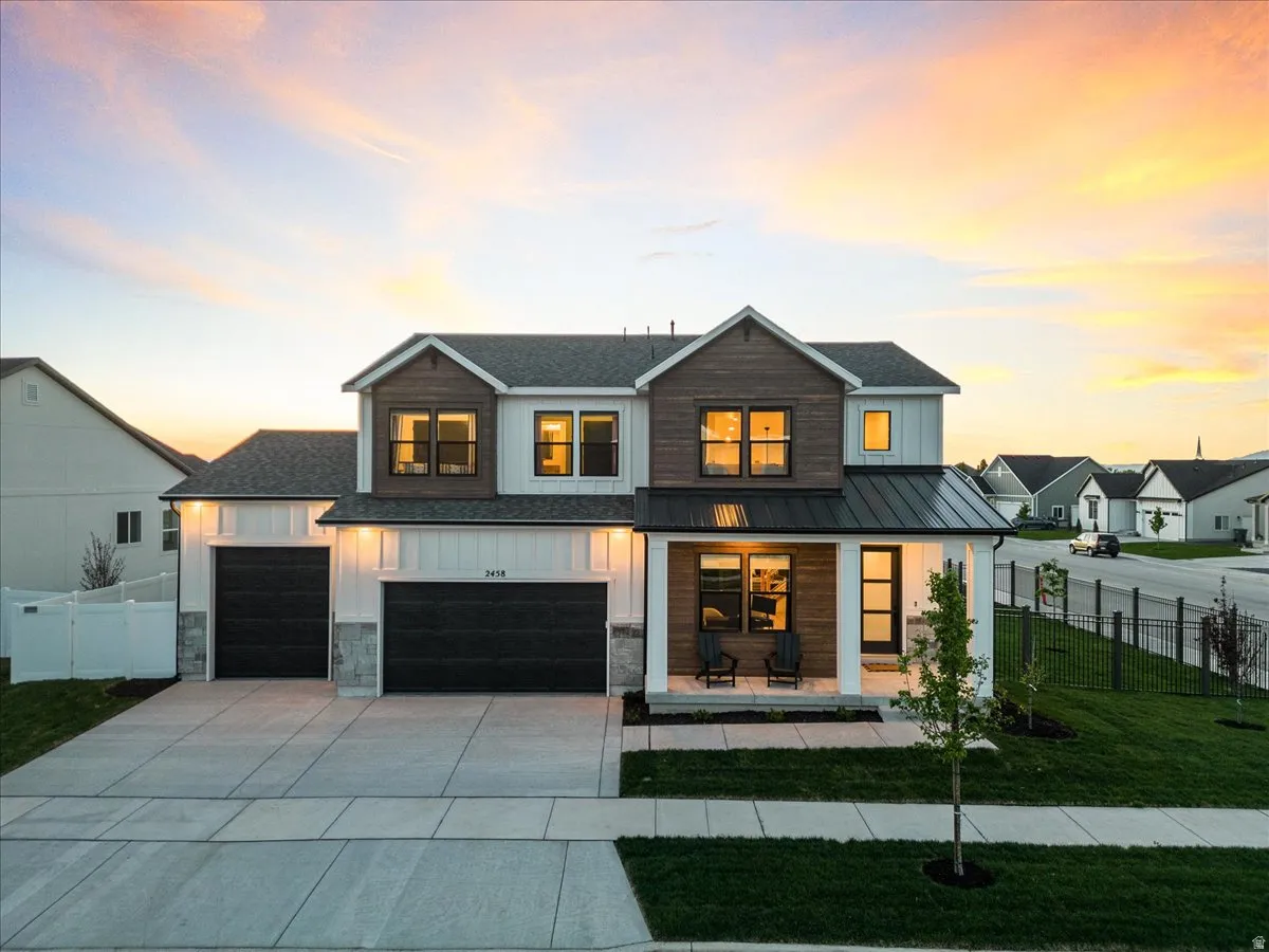 Modern farmhouse style home featuring covered porch, board and batten siding, driveway, and a metal roof