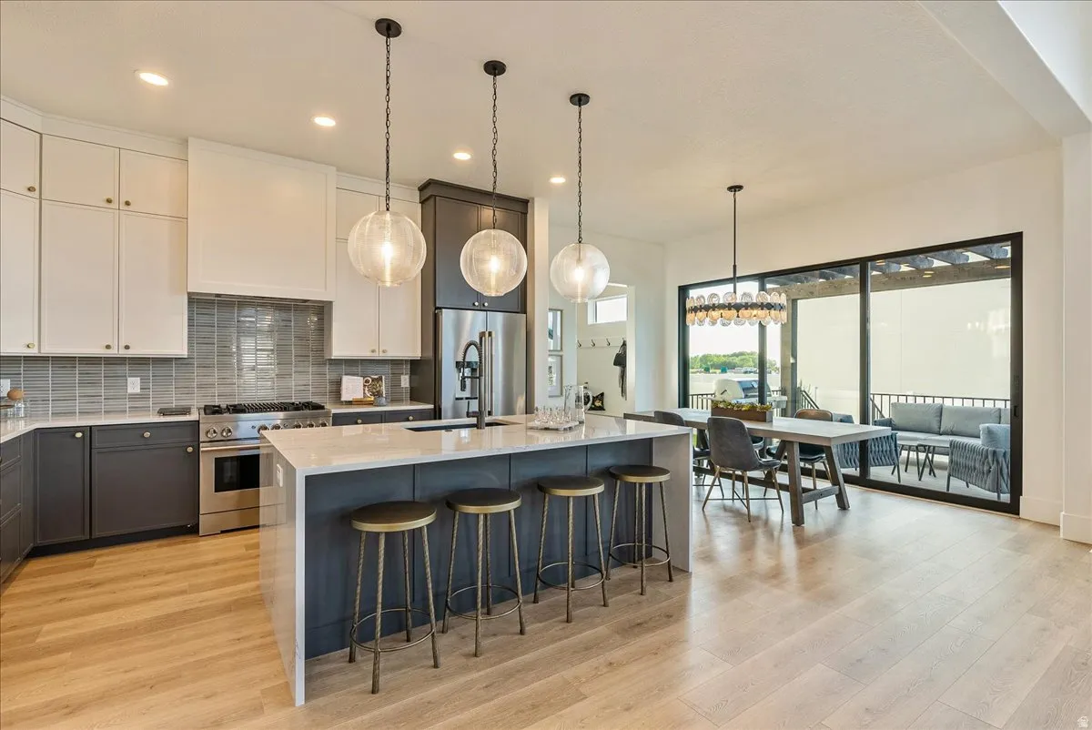 Kitchen with backsplash, light stone counters, pendant lighting, high end appliances, and recessed lighting