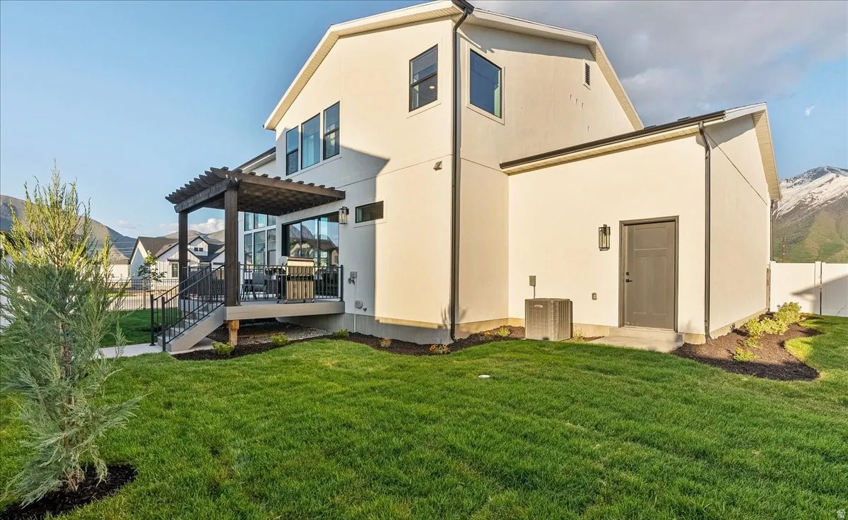 Rear view of house with stucco siding and a deck with mountain view