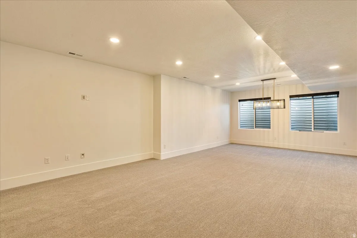 Empty room with light carpet, recessed lighting, and a textured ceiling
