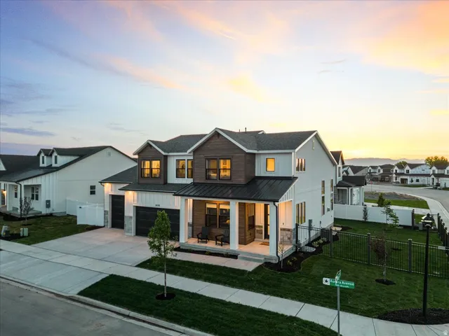 View of front of home featuring covered porch, driveway, a garage, a metal roof, and a residential view