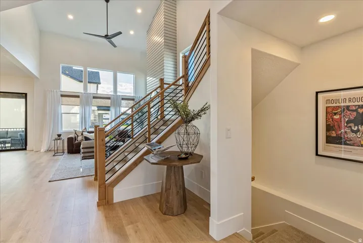 Staircase featuring recessed lighting, wood finished floors, a ceiling fan, and a high ceiling