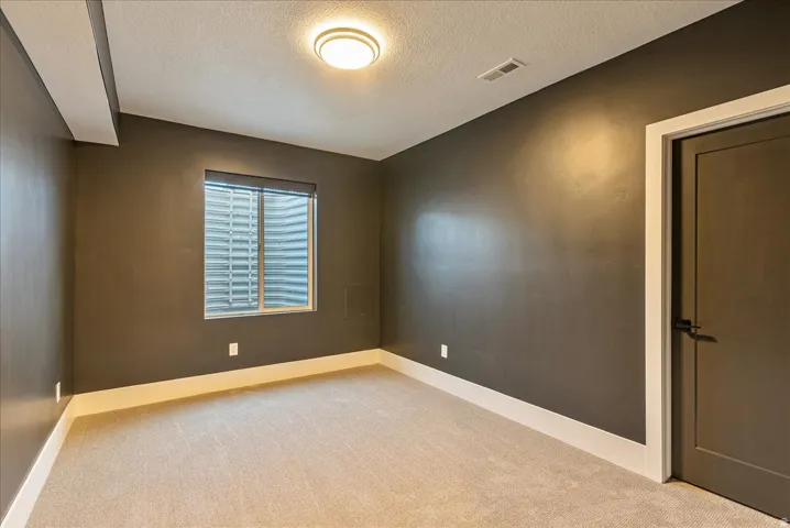 Empty room featuring carpet flooring and a textured ceiling