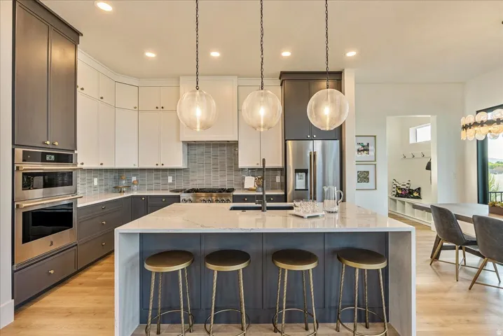 Kitchen featuring light stone countertops, hanging light fixtures, tasteful backsplash, a large island, and a breakfast bar area