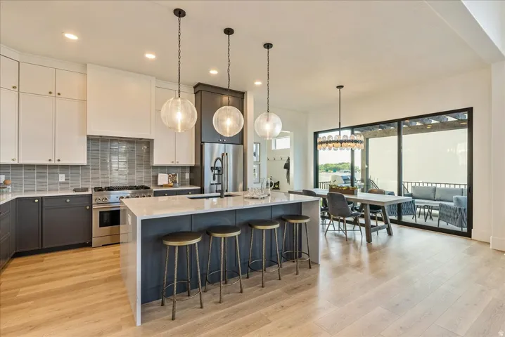 Kitchen with backsplash, light stone counters, pendant lighting, high end appliances, and recessed lighting
