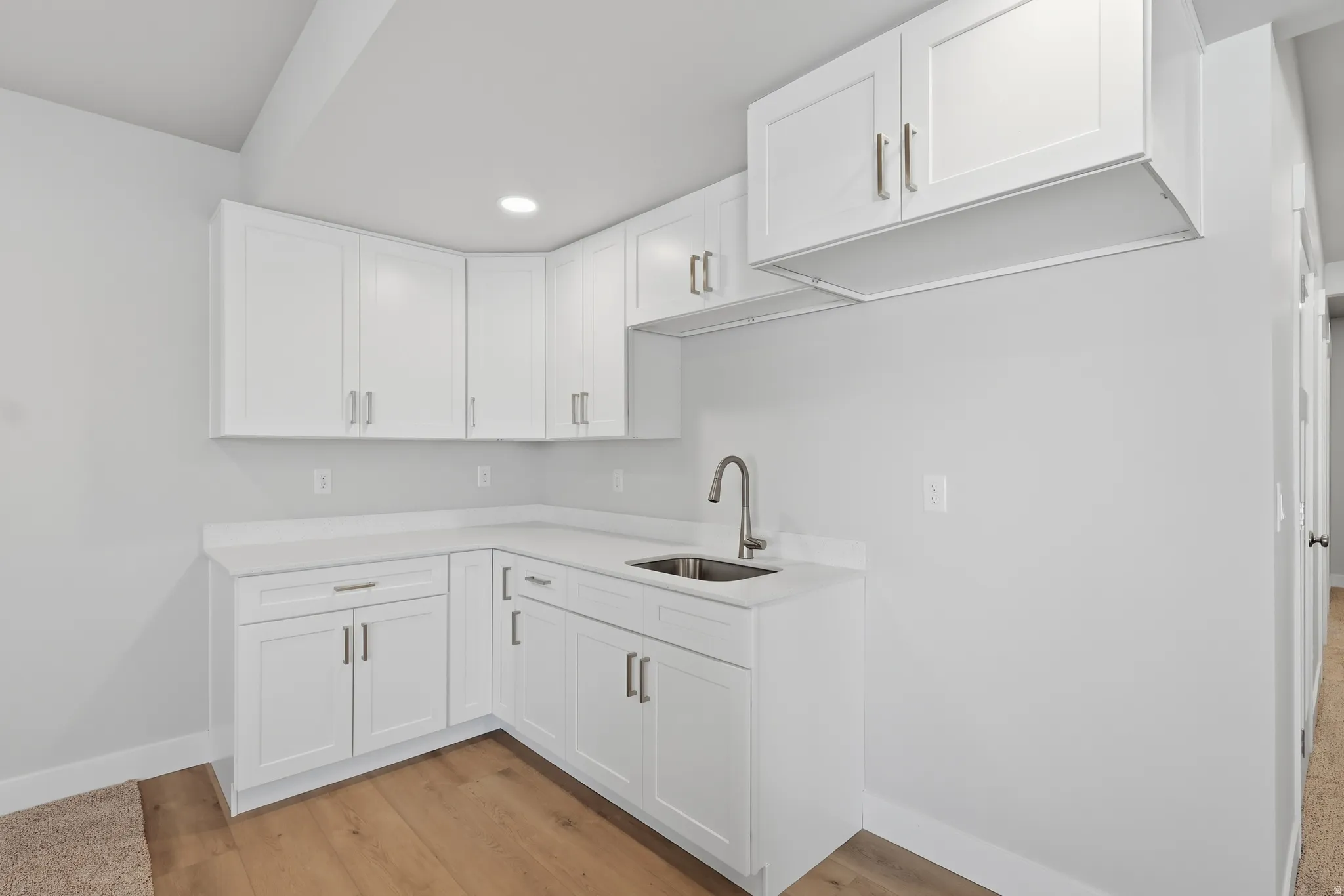 Kitchen with white cabinetry, light wood-type flooring, light stone countertops, and recessed lighting
