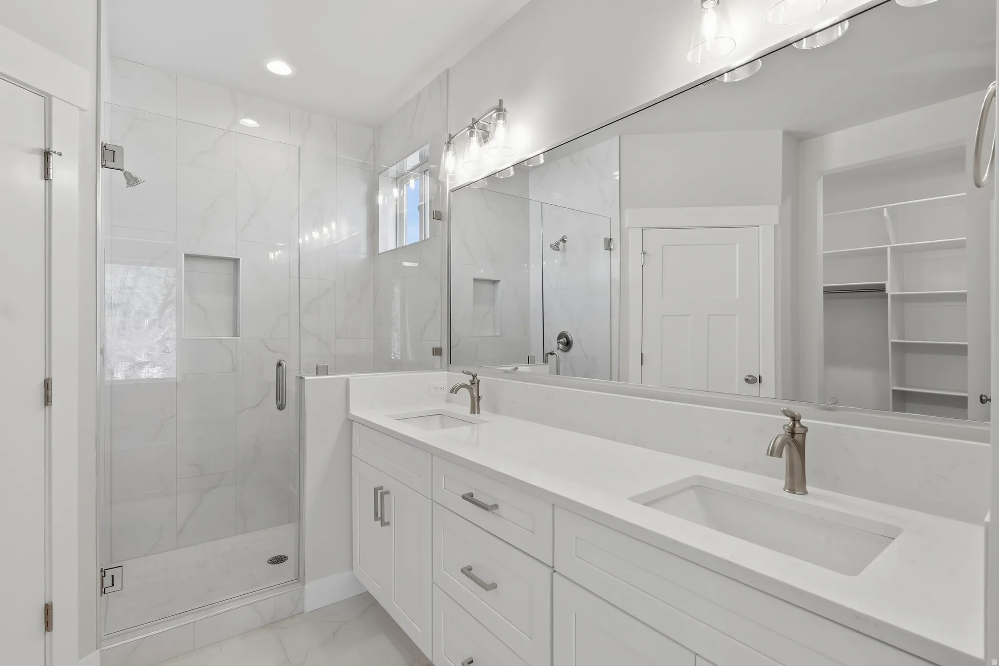 Bathroom with double vanity, a marble finish shower, a spacious closet, light marble finish floors, and recessed lighting