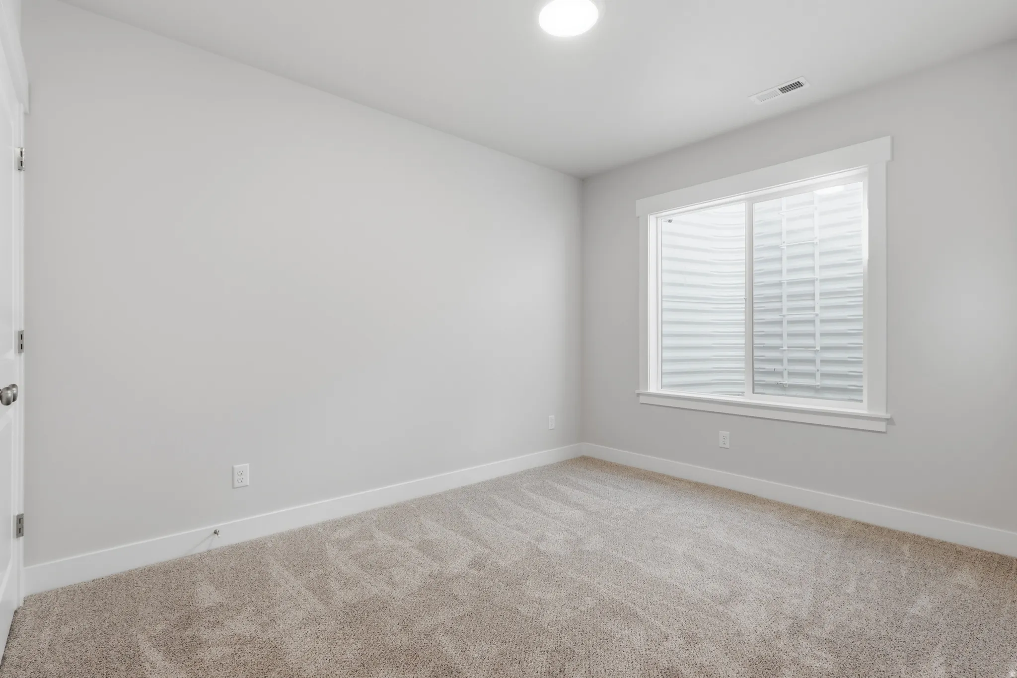 Unfurnished room featuring light carpet and baseboards