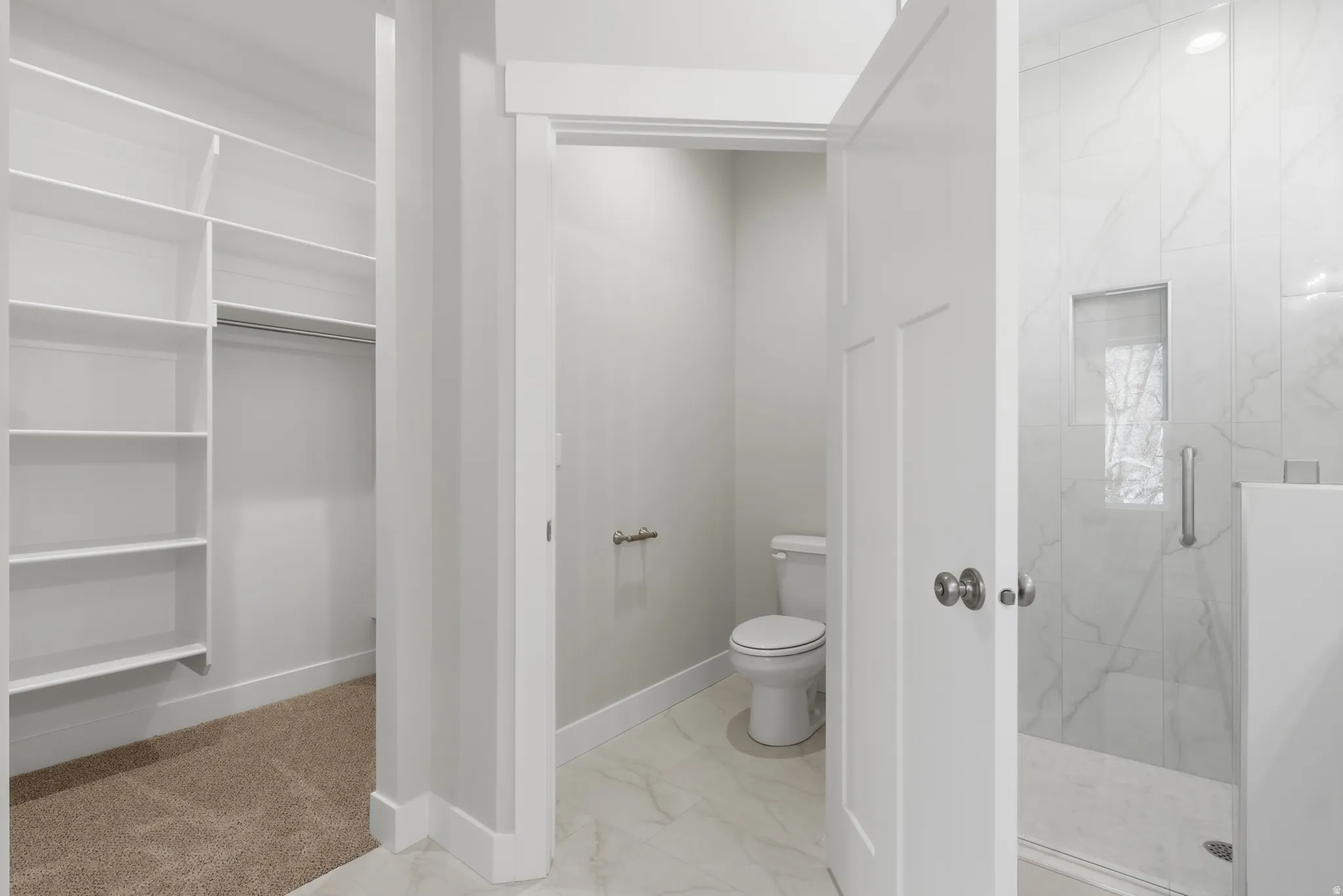 Bathroom featuring light marble finish flooring and a marble finish shower