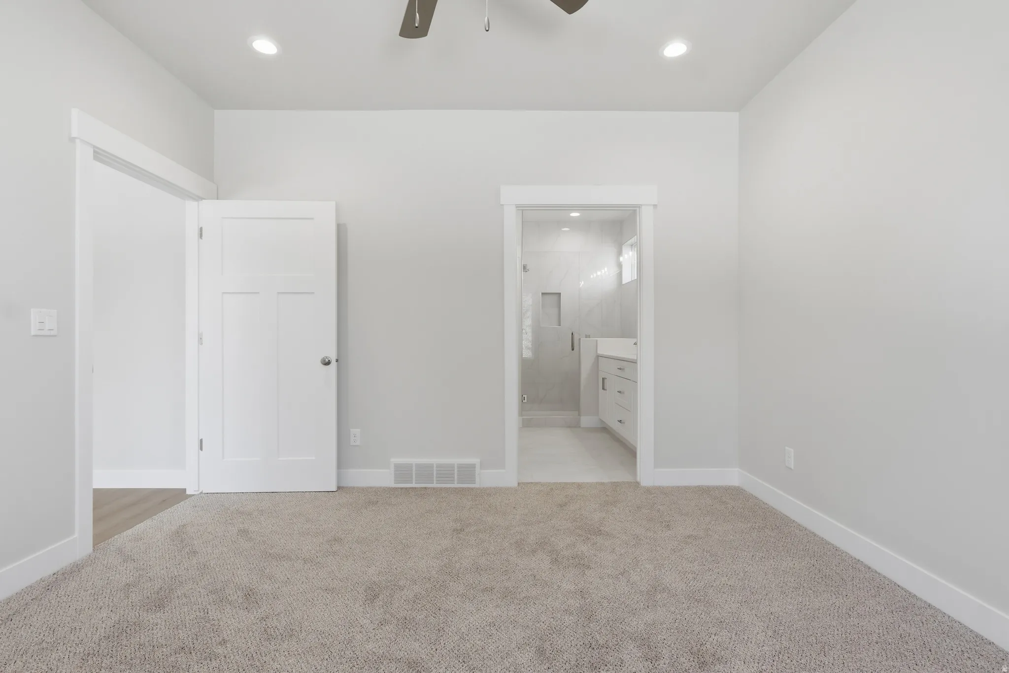 Unfurnished bedroom featuring light carpet, ensuite bathroom, recessed lighting, and ceiling fan