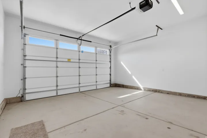 Garage featuring a garage door opener and baseboards