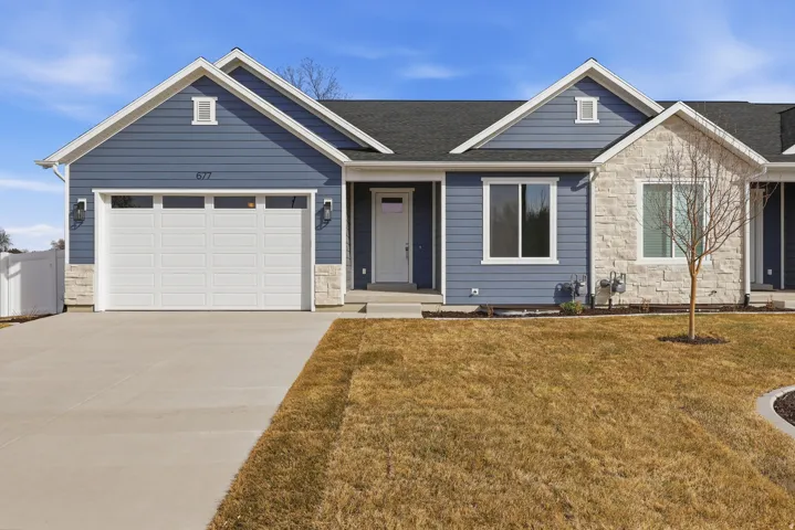 Ranch-style house with stone siding, driveway, a front yard, and an attached garage
