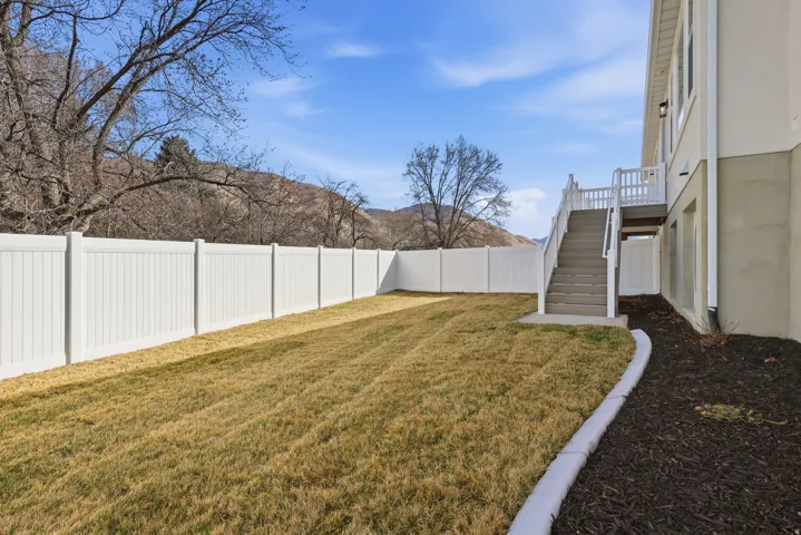 Fenced backyard featuring stairway and a deck with mountain view