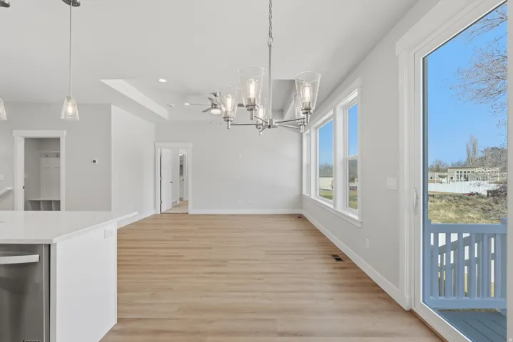 Unfurnished dining area with hanging lights, light wood-style floors, and a raised ceiling