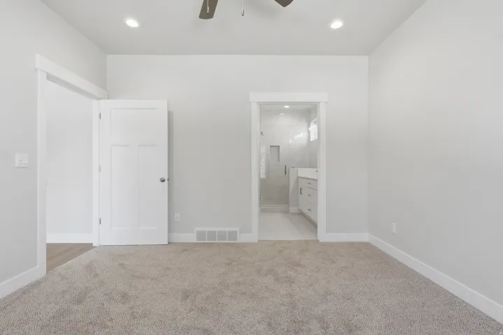 Unfurnished bedroom featuring light carpet, ensuite bathroom, recessed lighting, and ceiling fan