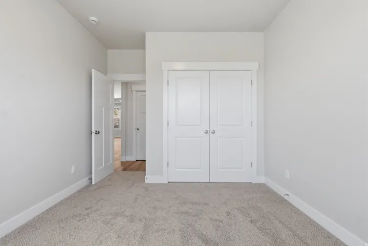 Unfurnished bedroom with light colored carpet and a closet