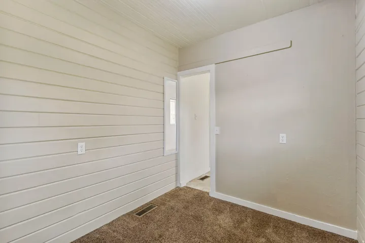 Empty room with carpet flooring and wood walls