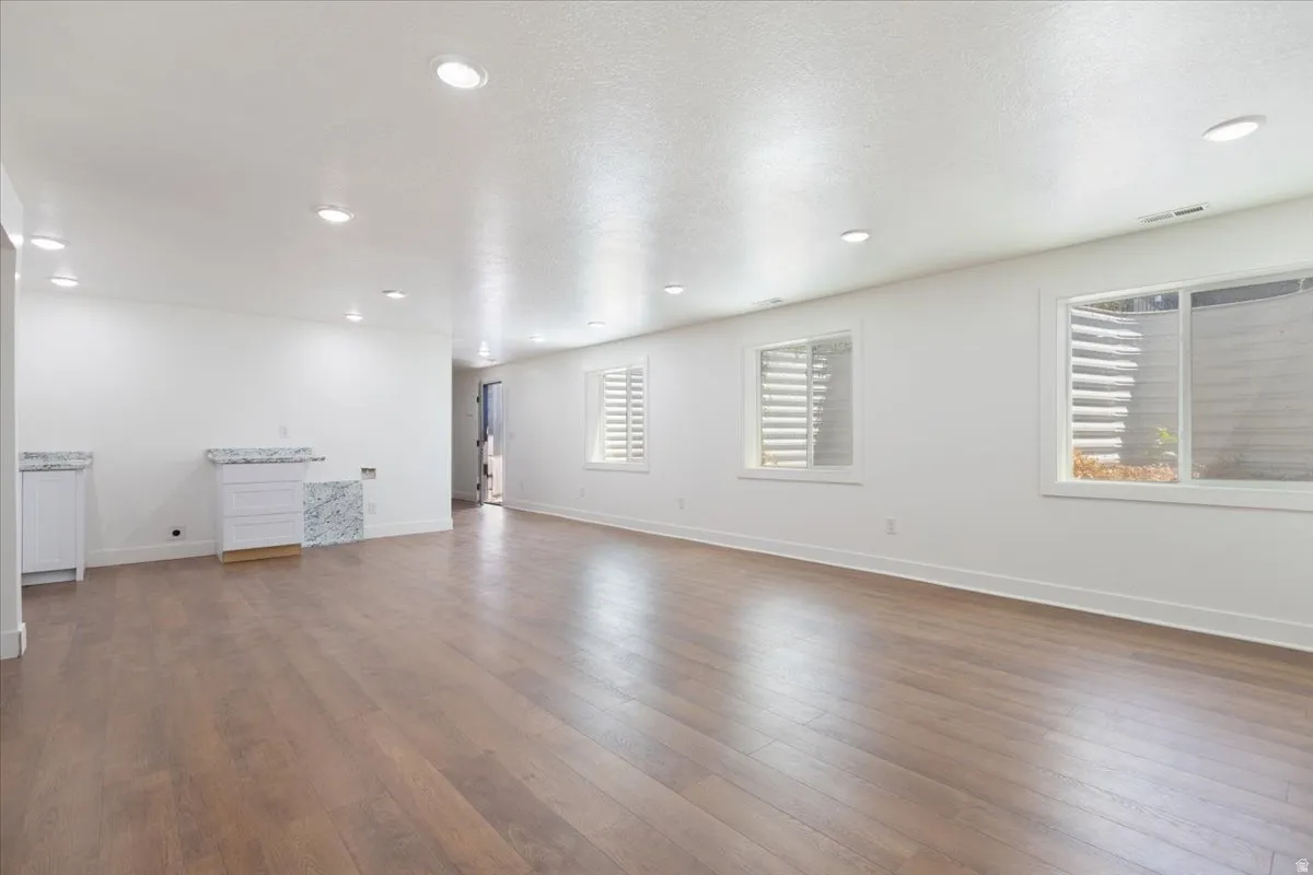 Unfurnished living room with dark wood-type flooring, recessed lighting, and a textured ceiling