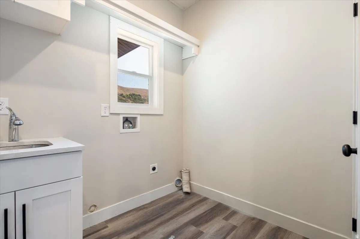 Washroom with dark wood-type flooring, washer hookup, cabinet space, and electric dryer hookup