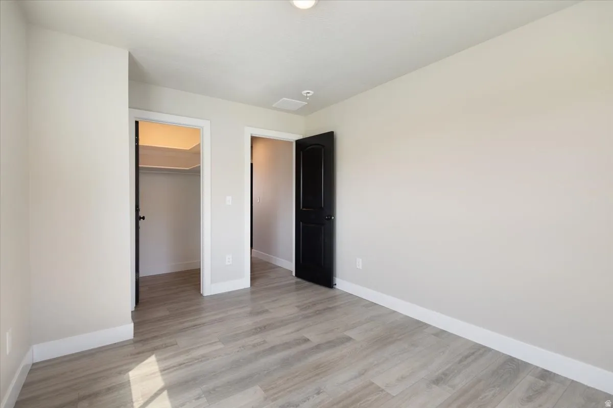 Unfurnished bedroom featuring light wood finished floors and a walk in closet