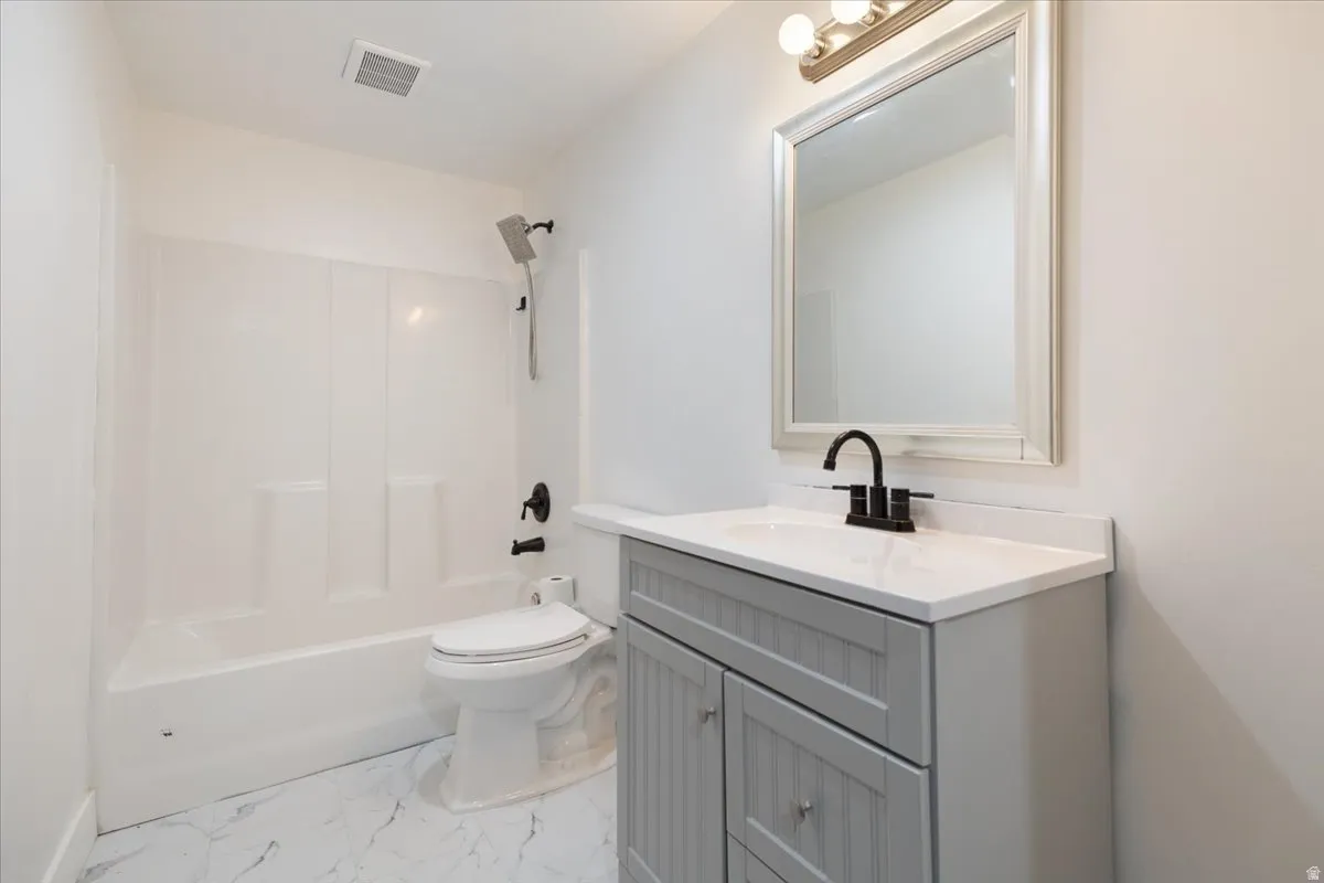 Full bathroom featuring vanity,  shower combination, and light marble finish flooring