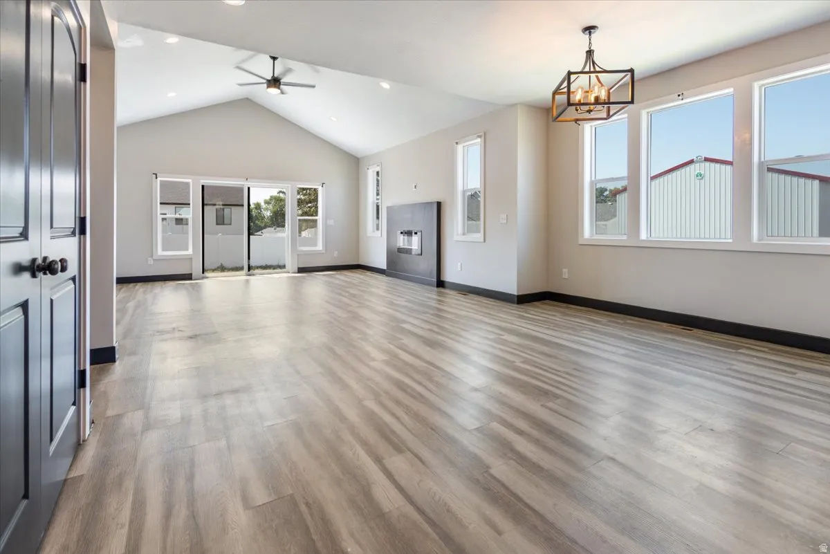 Unfurnished living room with light wood-type flooring, a ceiling fan, recessed lighting, and high vaulted ceiling