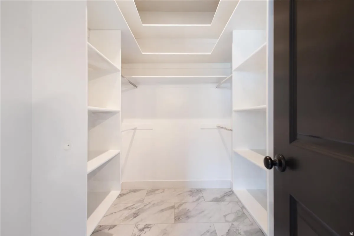 Spacious closet featuring light marble finish floors