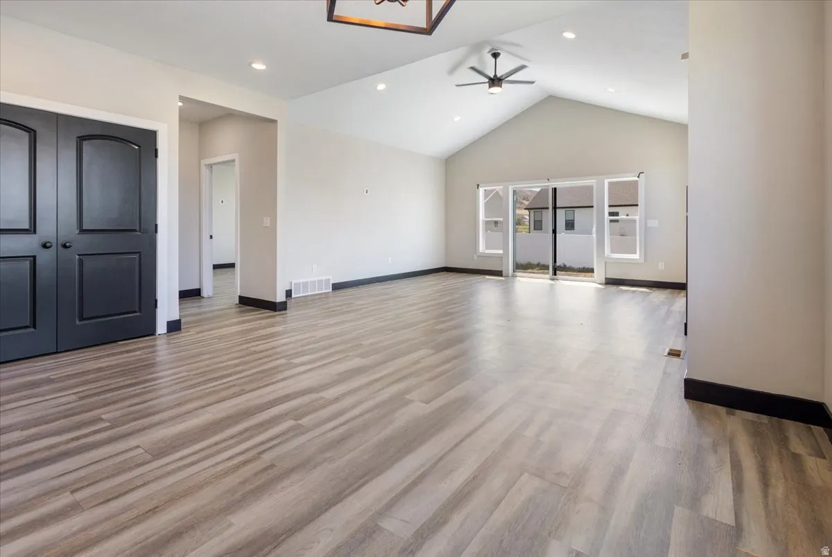 Unfurnished living room with high vaulted ceiling, light wood-style flooring, ceiling fan, and recessed lighting