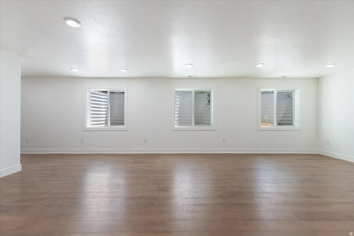 Empty room with healthy amount of natural light, dark wood-type flooring, and a textured ceiling