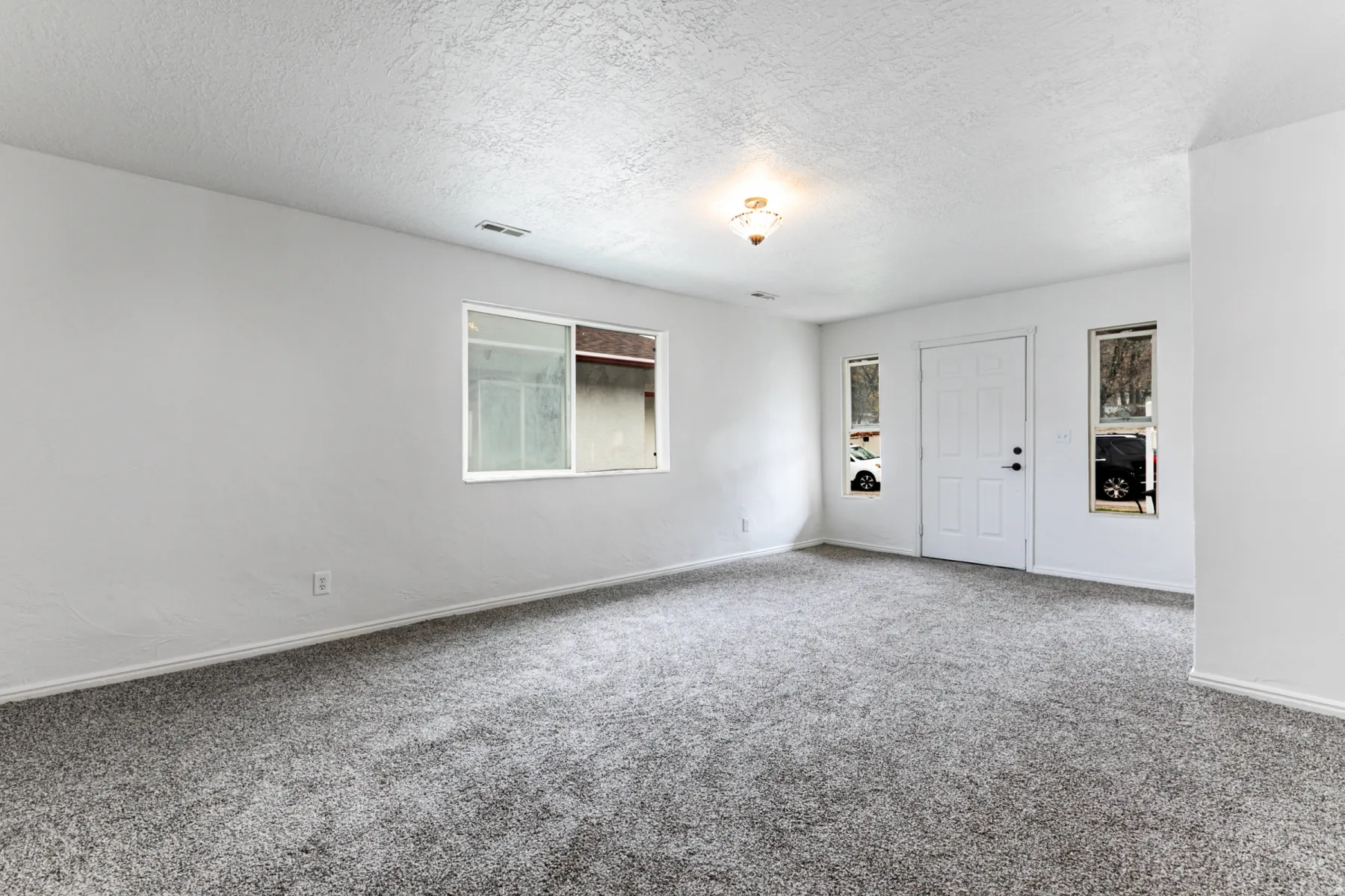 Carpeted spare room featuring a textured ceiling and baseboards