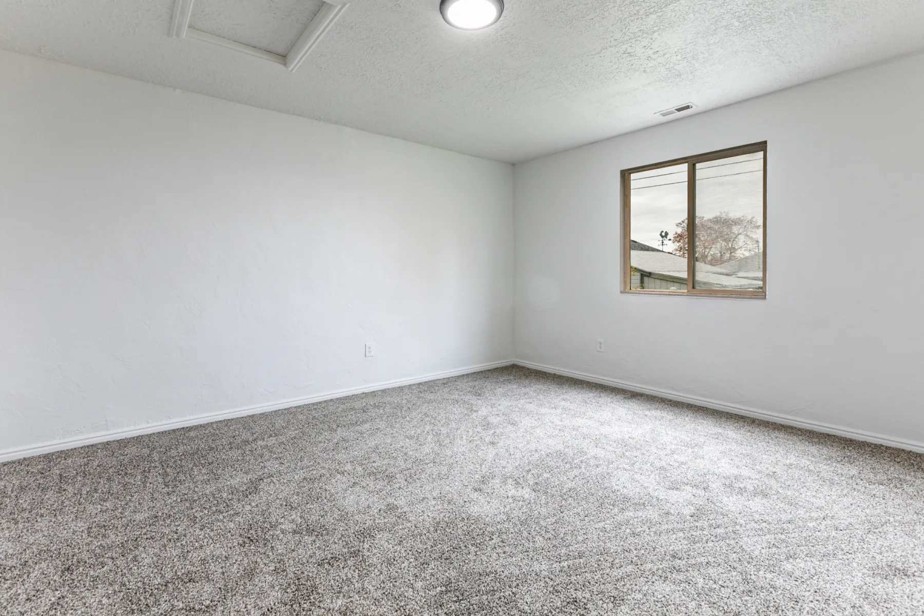 Carpeted empty room with a textured ceiling and baseboards