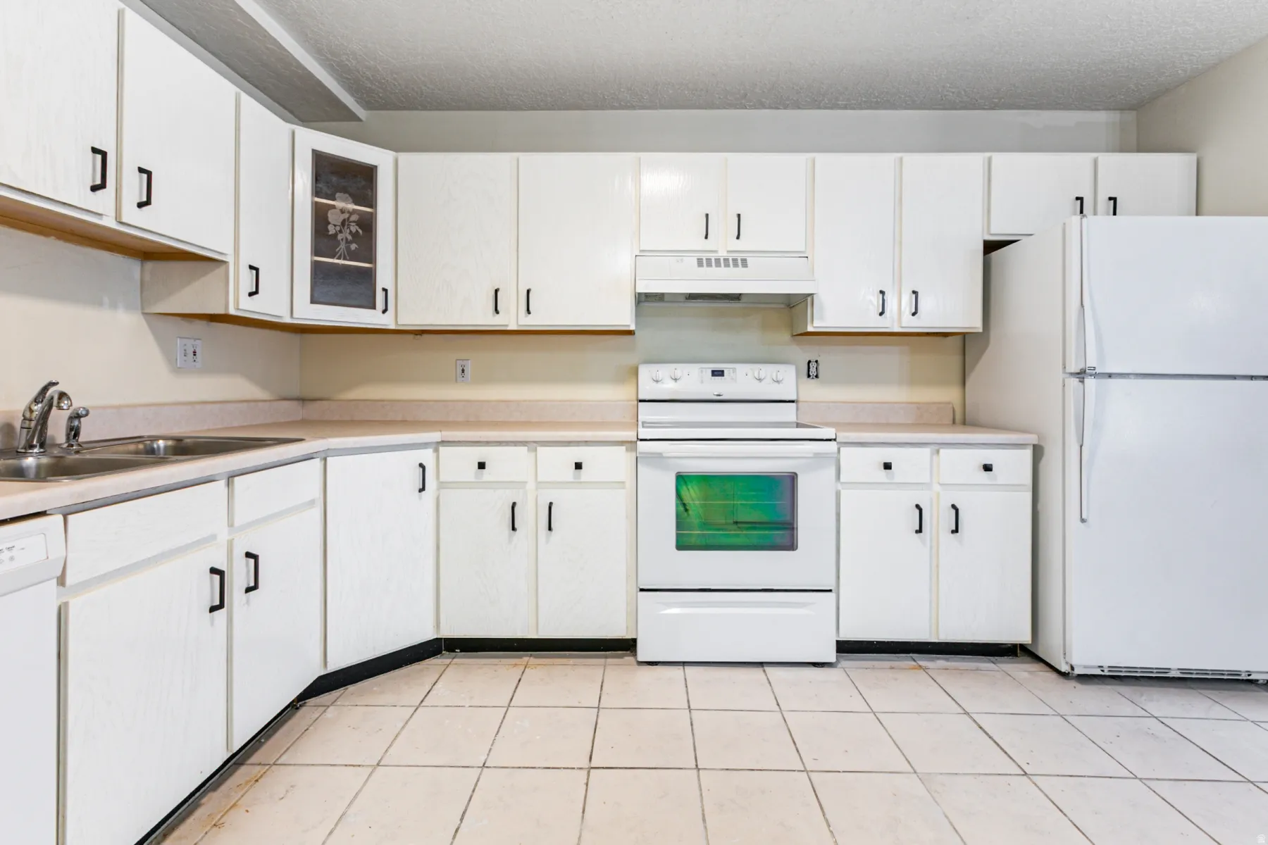 Kitchen featuring white appliances, light countertops, glass insert cabinets, under cabinet range hood, and light tile patterned floors