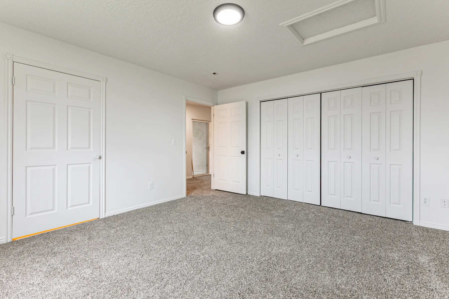 Unfurnished bedroom featuring attic access, carpet flooring, a closet, and a textured ceiling