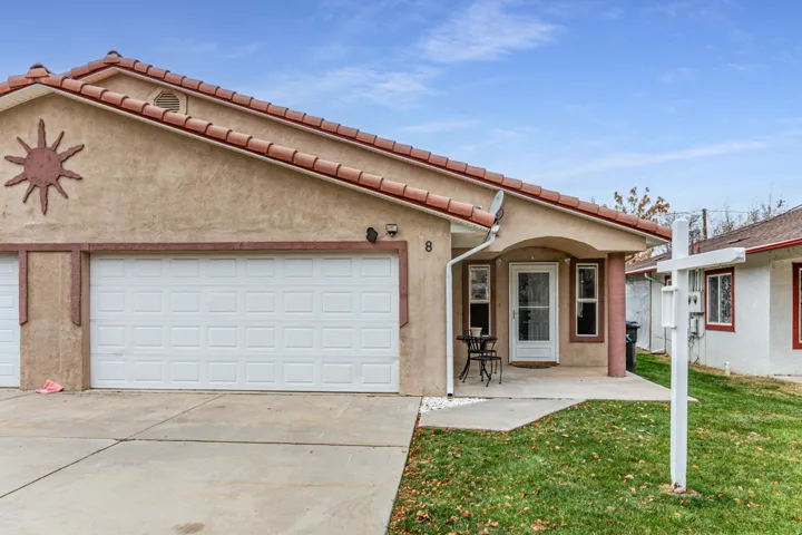 Mediterranean / spanish house featuring stucco siding, concrete driveway, a patio, an attached garage, and a front lawn