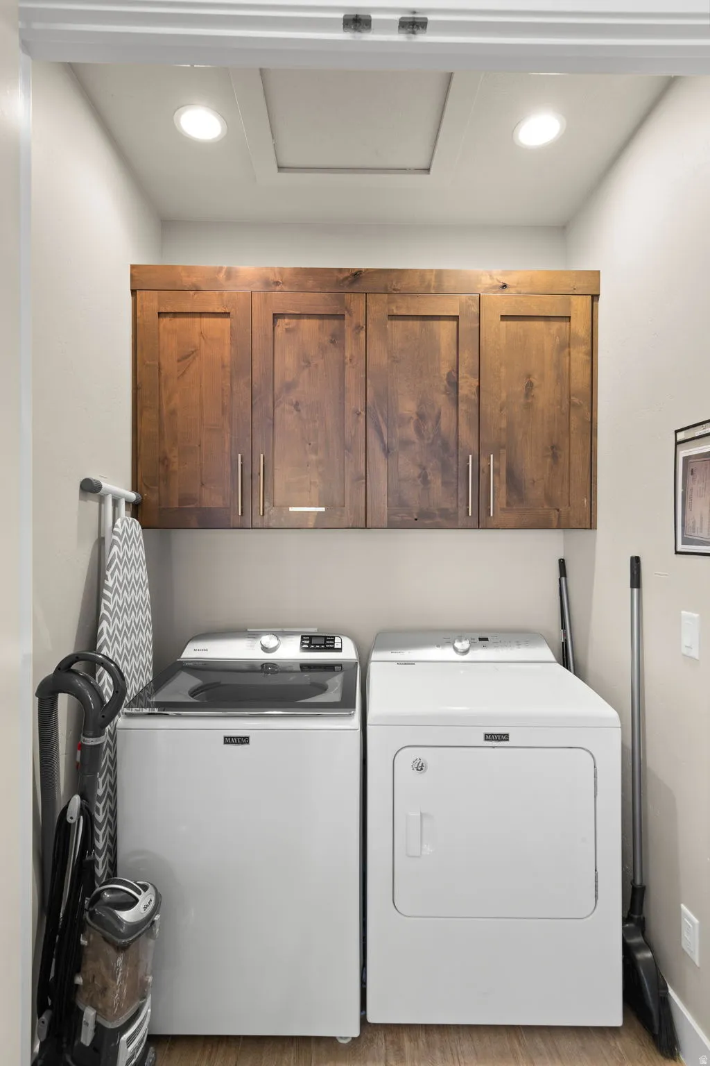 Laundry area with cabinet space, washing machine and dryer, wood finished floors, and recessed lighting