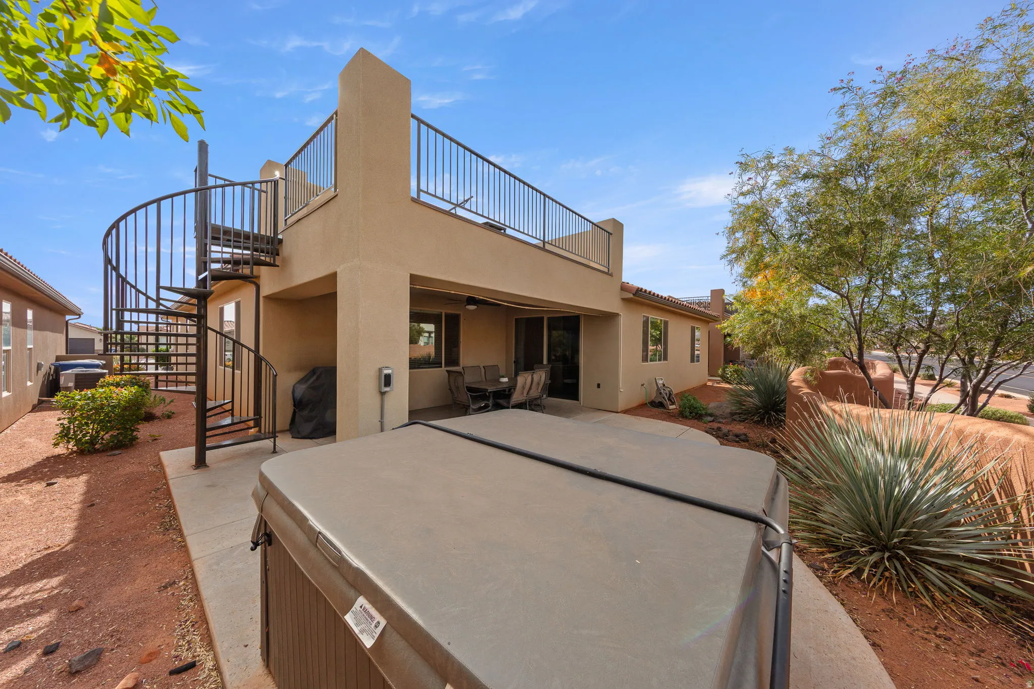 Back of house featuring stairway, a hot tub, stucco siding, a patio, and a ceiling fan