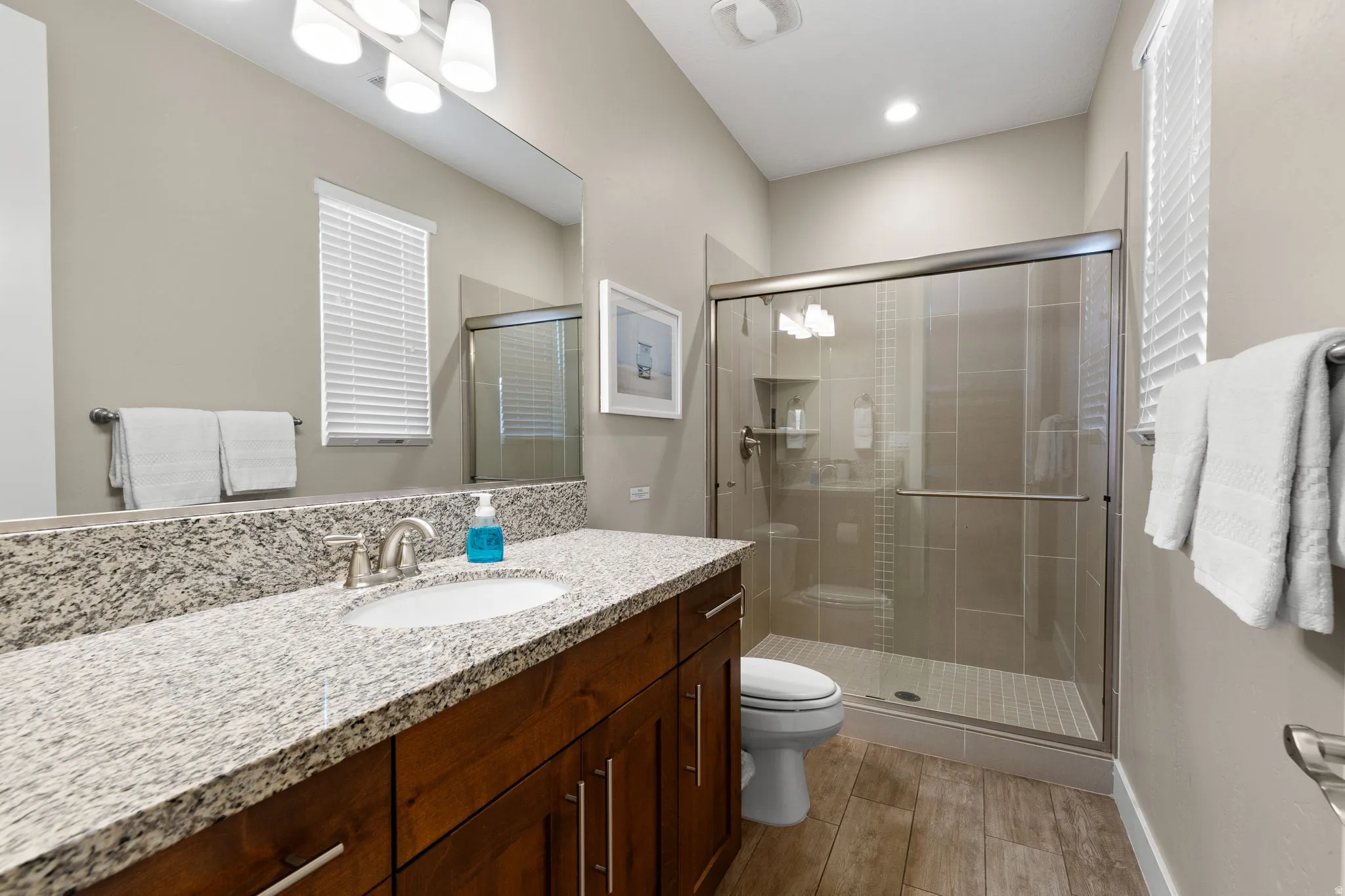 Bathroom with vanity, a shower stall, and light wood-type flooring