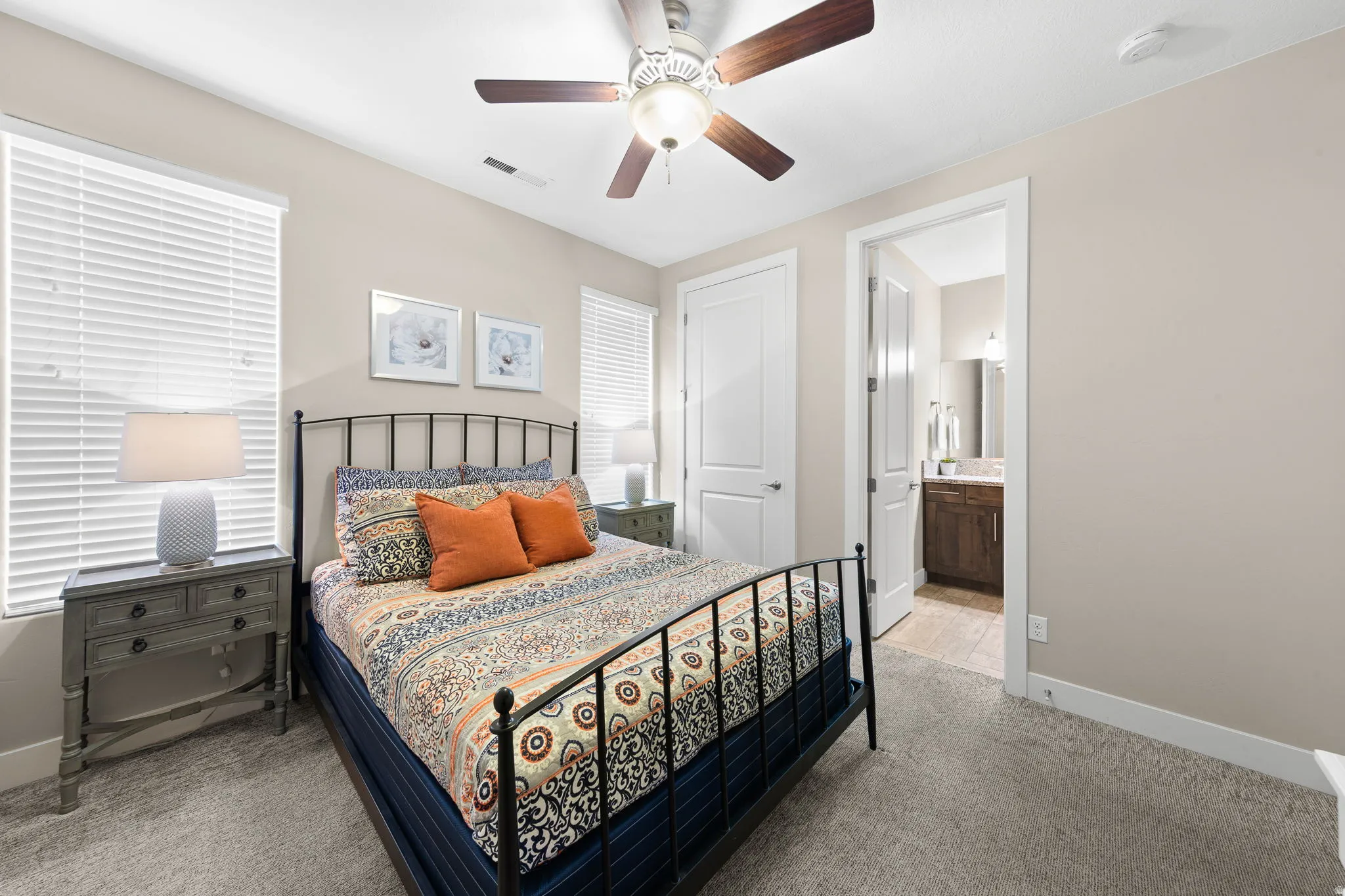 Bedroom featuring light carpet, a ceiling fan, and connected bathroom