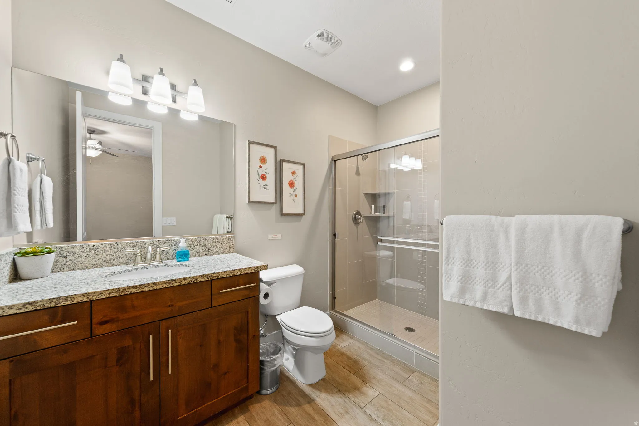 Bathroom with vanity, a stall shower, light wood-style flooring, and ceiling fan
