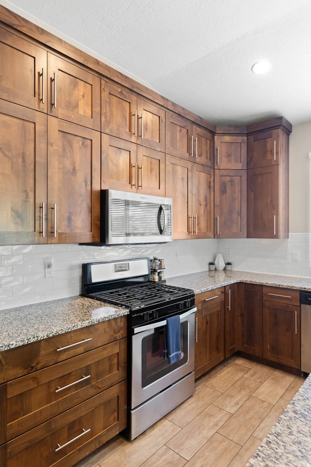 Kitchen with appliances with stainless steel finishes, backsplash, light stone countertops, a textured ceiling, and recessed lighting
