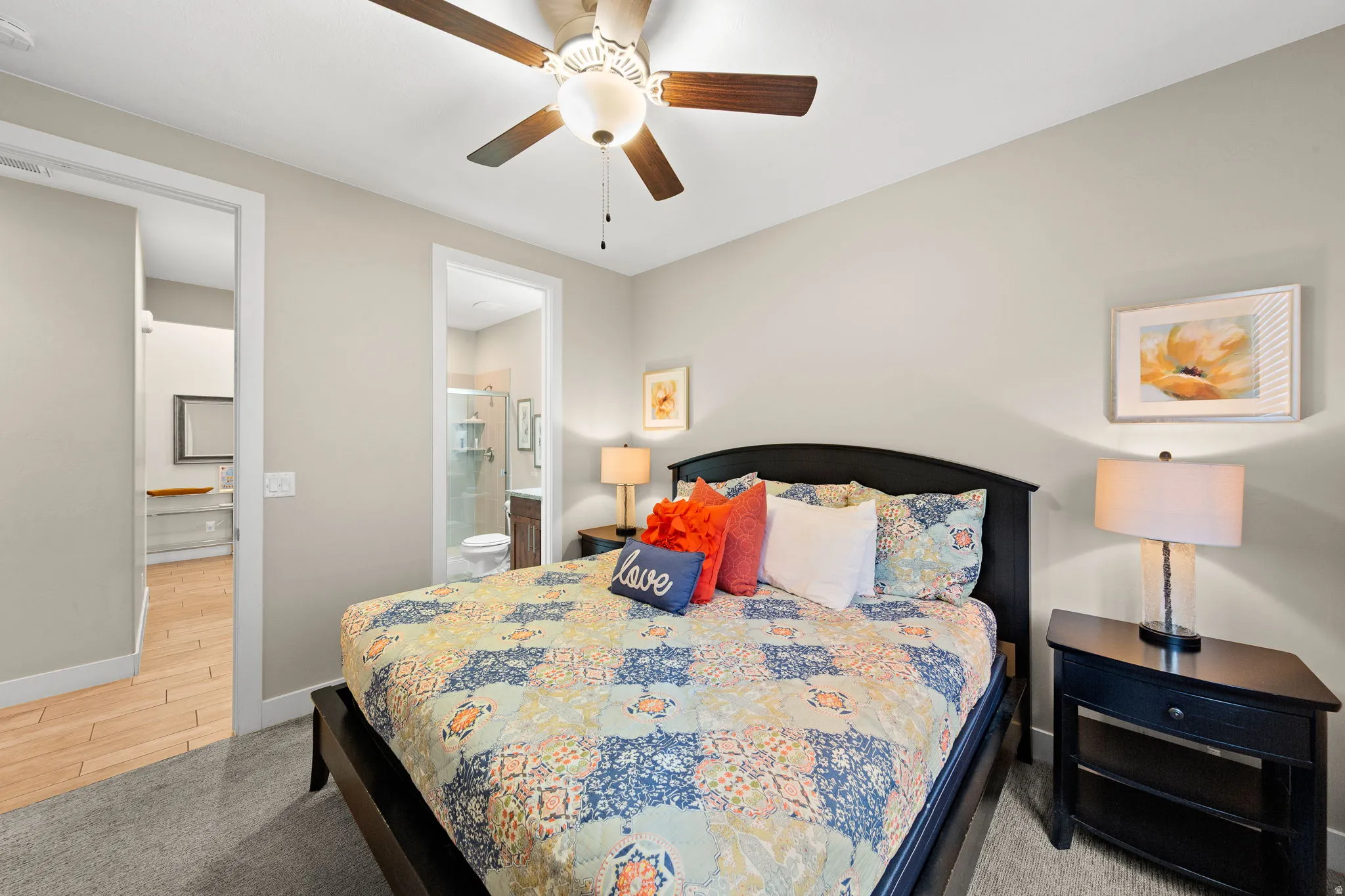 Bedroom featuring light colored carpet, ensuite bath, and a ceiling fan