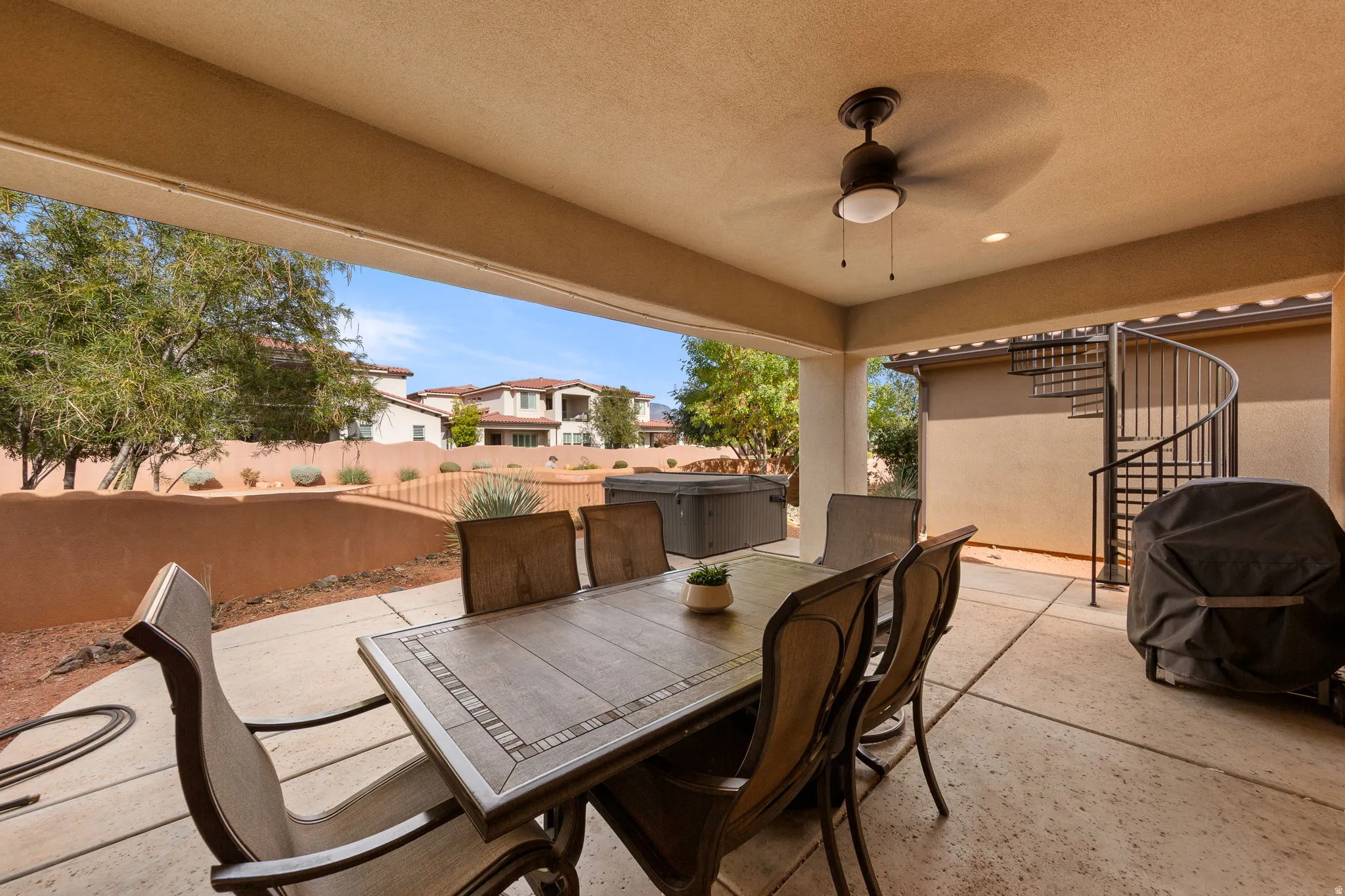 Fenced backyard with outdoor dining space, a patio area, a ceiling fan, and grilling area
